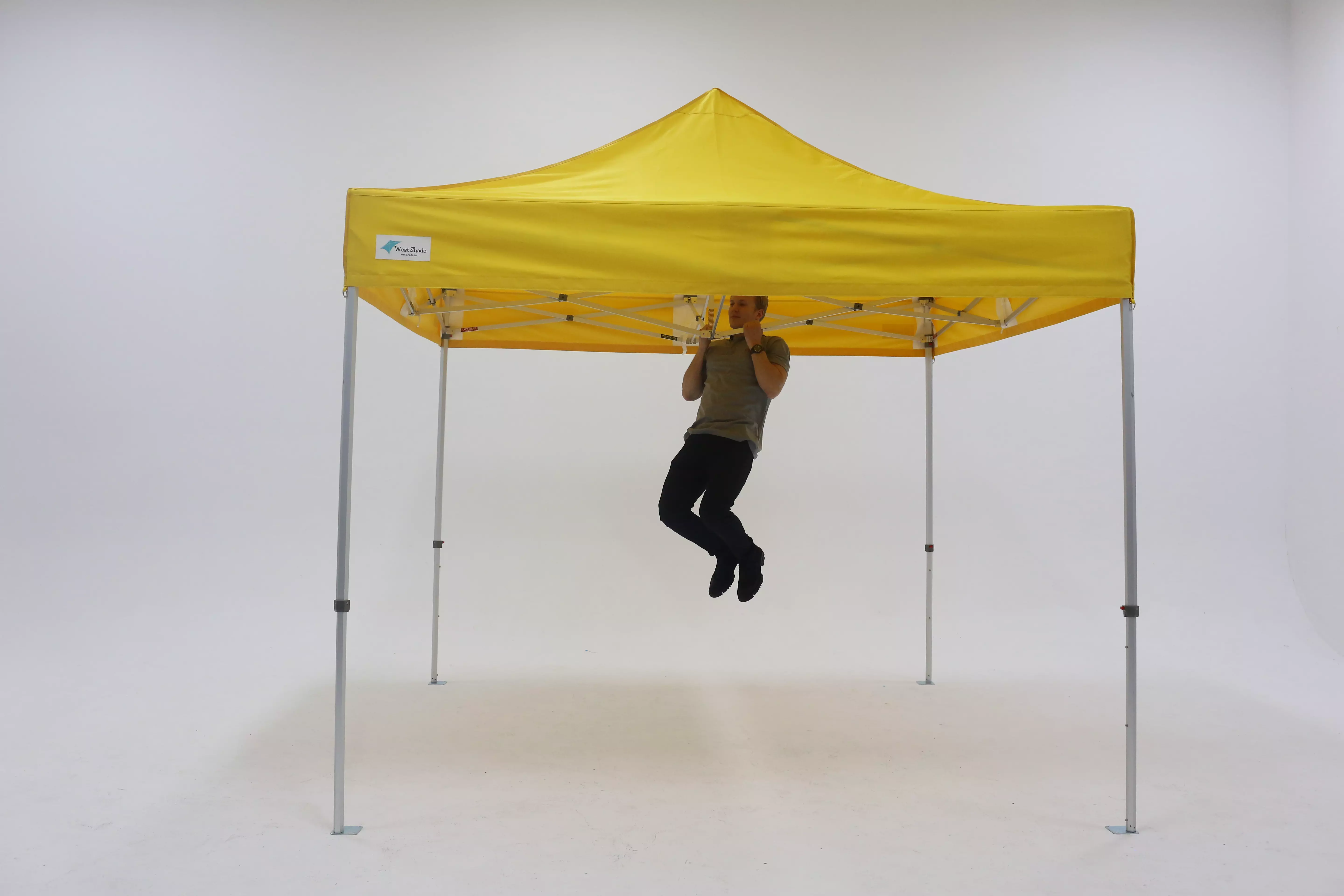 An adult man using a yellow tent to do pull-ups