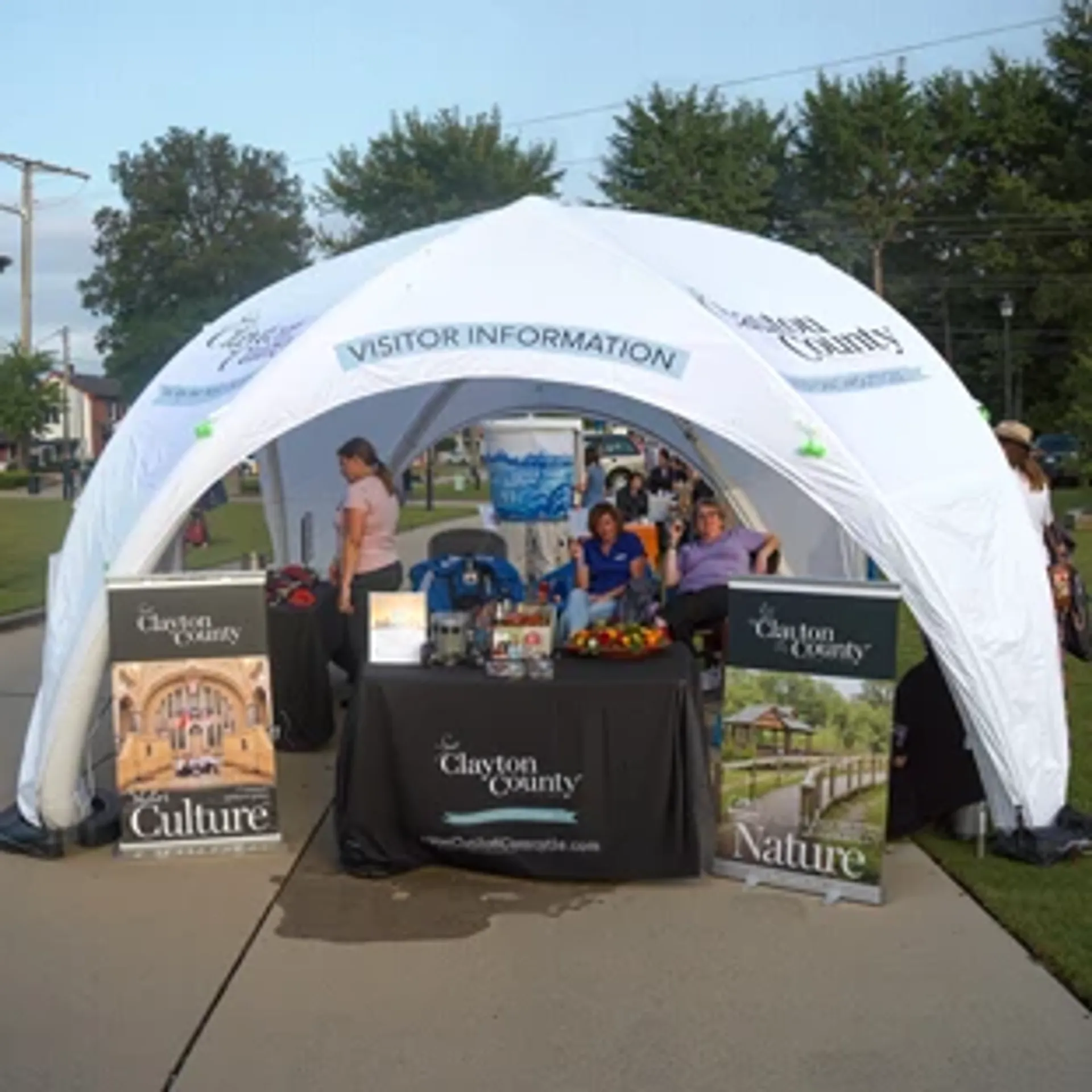 White custom inflatable canopy tent used as an outdoor visitor information booth and tourism display with branded banners