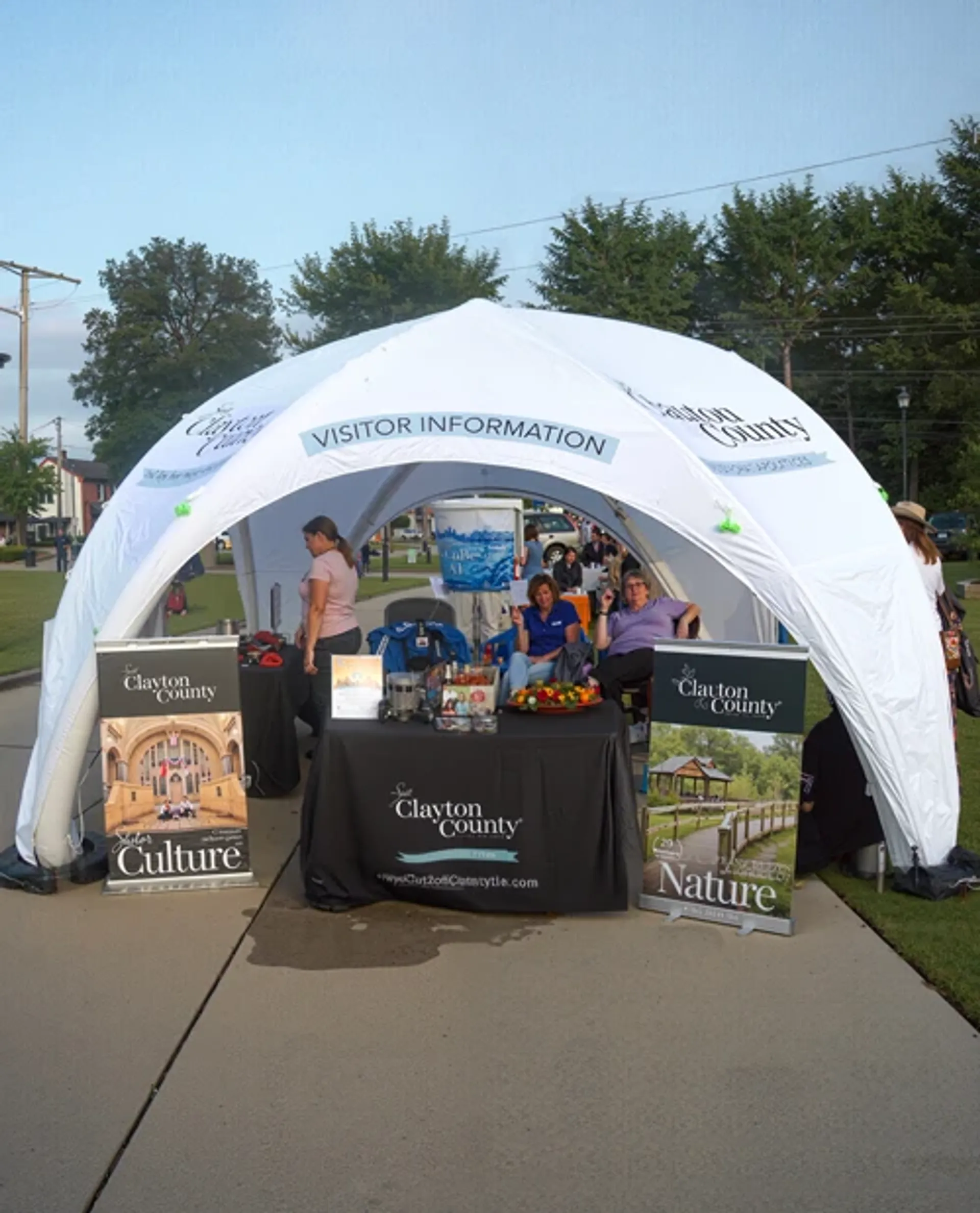 White custom inflatable canopy tent used as an outdoor visitor information booth and tourism display with branded banners