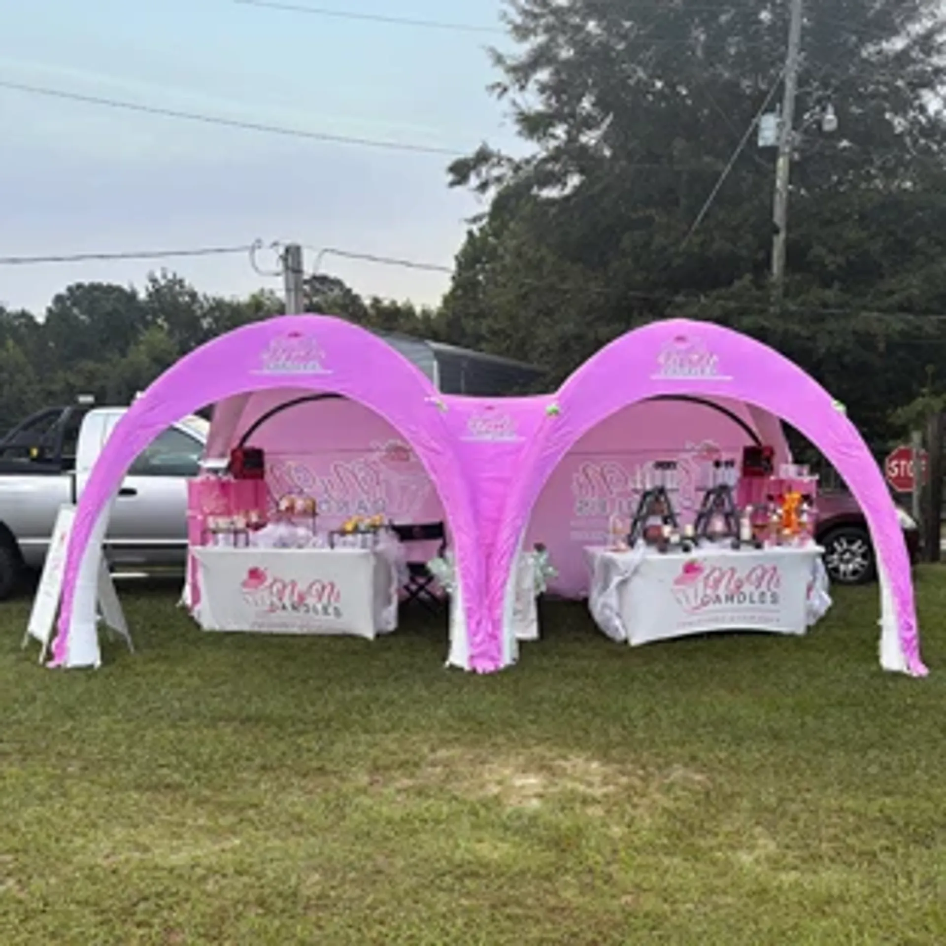 Pink connected custom inflatable event tent serving as an outdoor vendor booth and pop-up shop for a candle brand