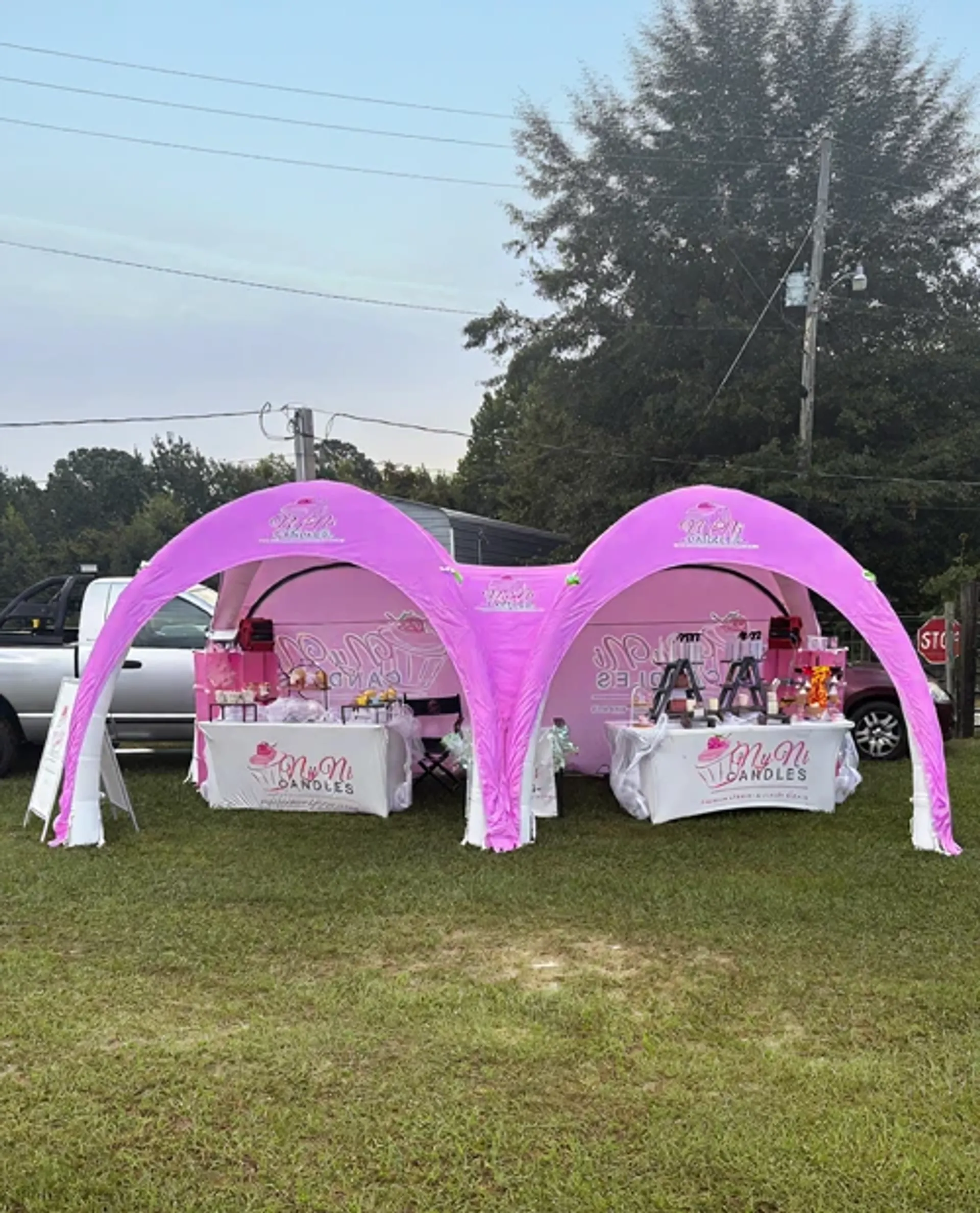Pink connected custom inflatable event tent serving as an outdoor vendor booth and pop-up shop for a candle brand