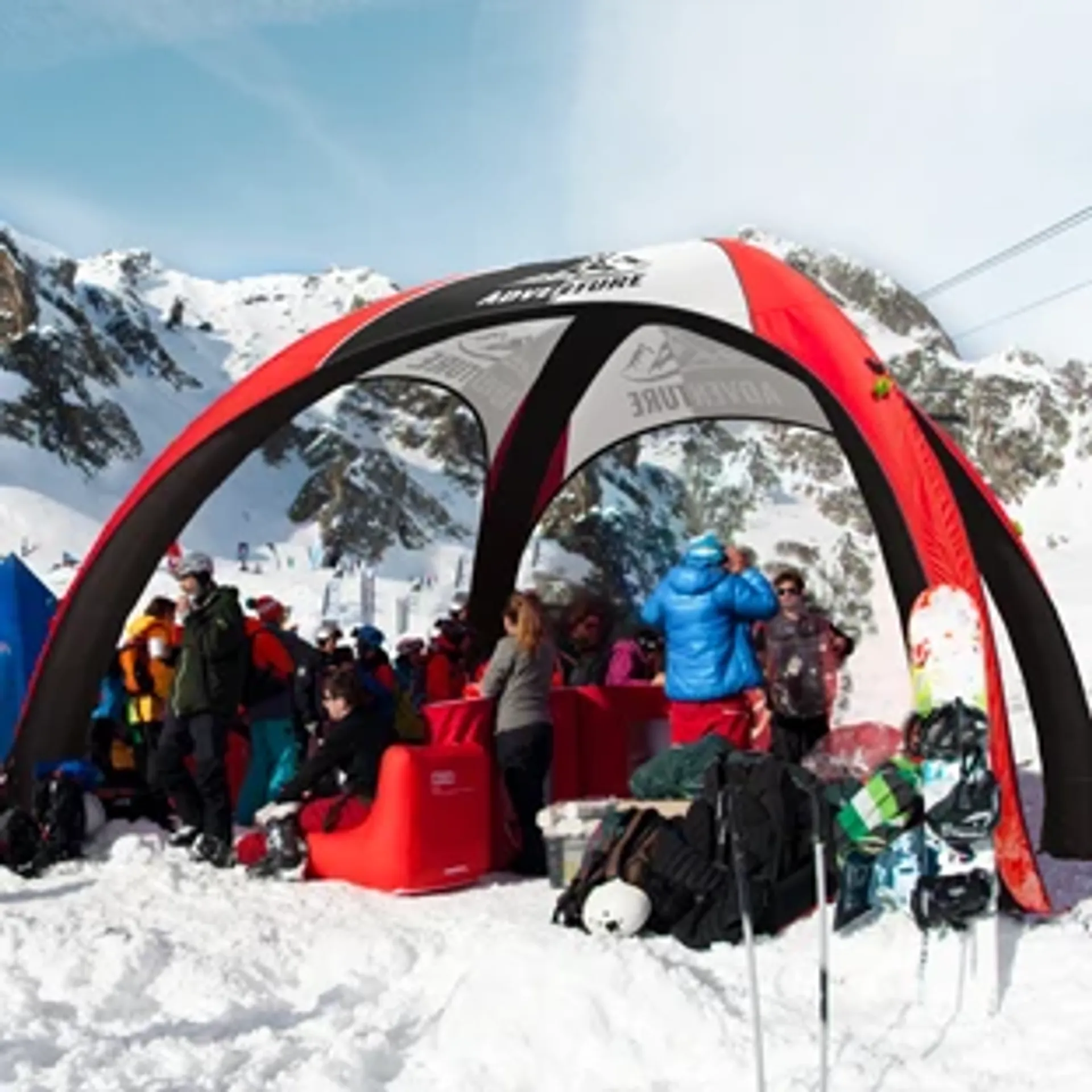 Custom inflatable event tent in red and black used as a branded winter lounge and shelter at a snowy mountain ski resort