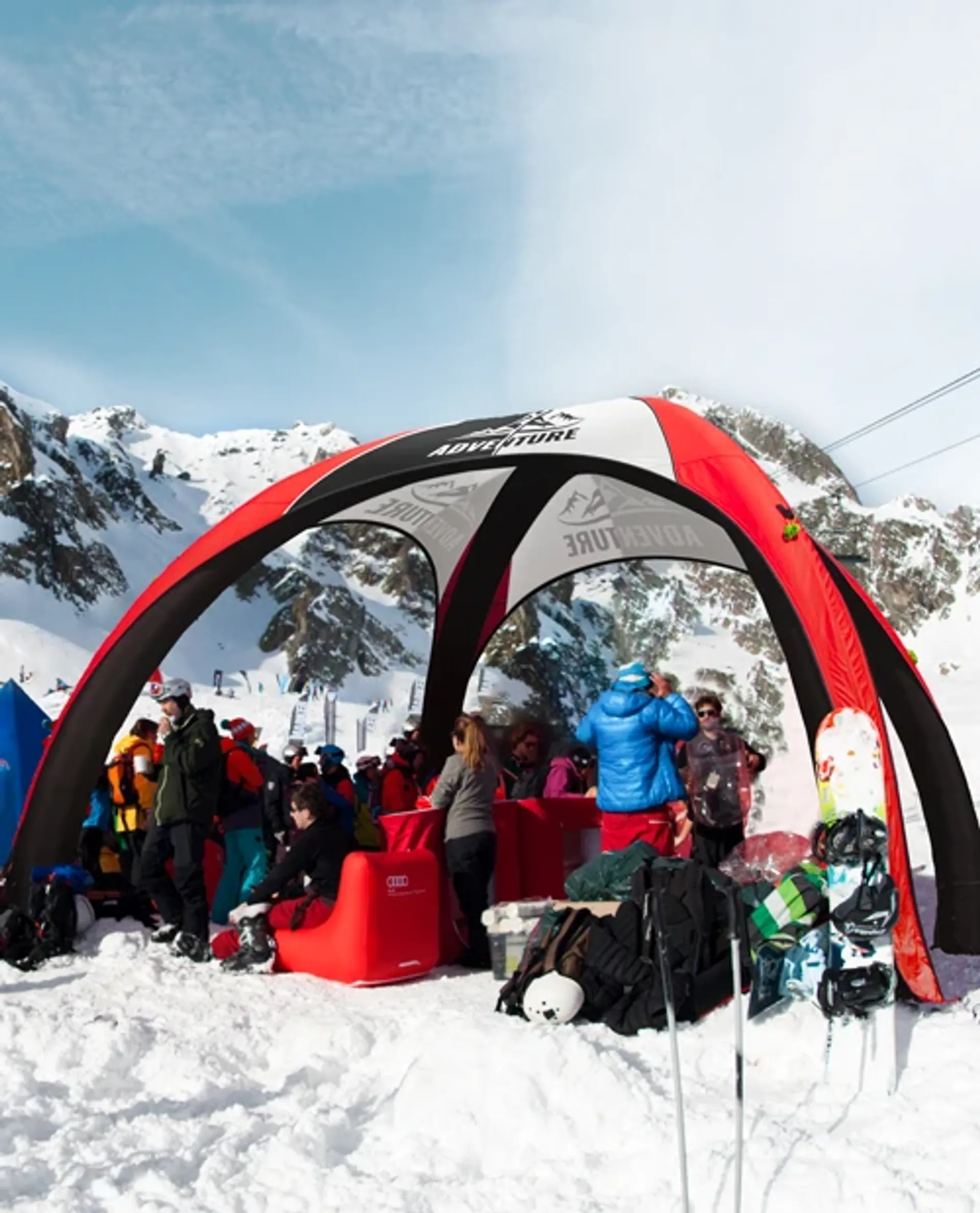 Custom inflatable event tent in red and black used as a branded winter lounge and shelter at a snowy mountain ski resort
