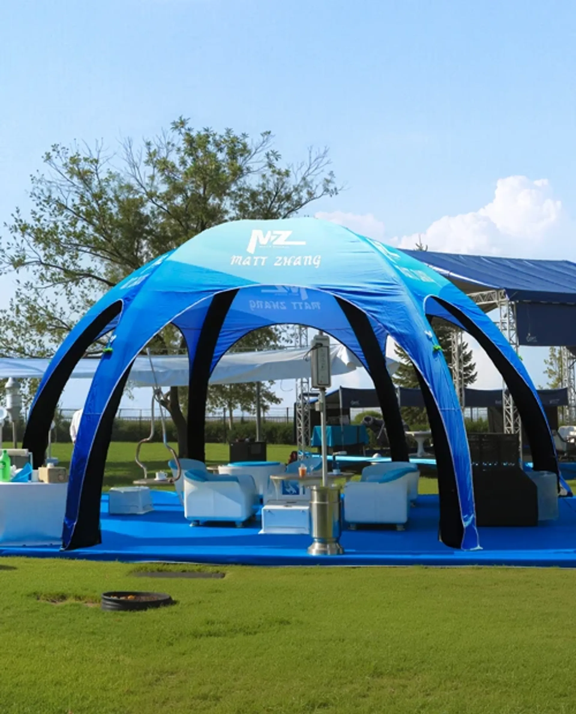Bright blue custom inflatable event dome set up as an outdoor VIP lounge and hospitality area with modern white seating