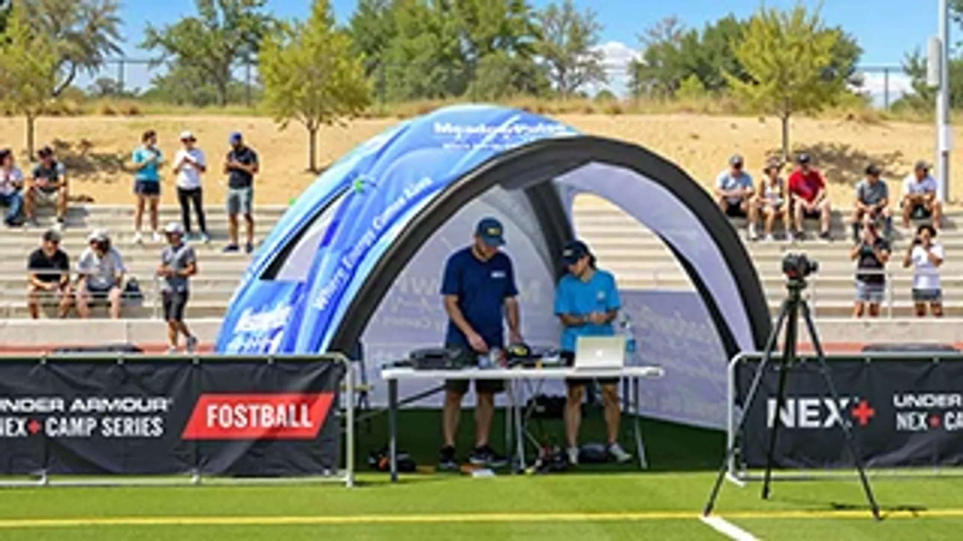 Custom inflatable sports tent providing shade for a media and timing station at an outdoor athletic training camp