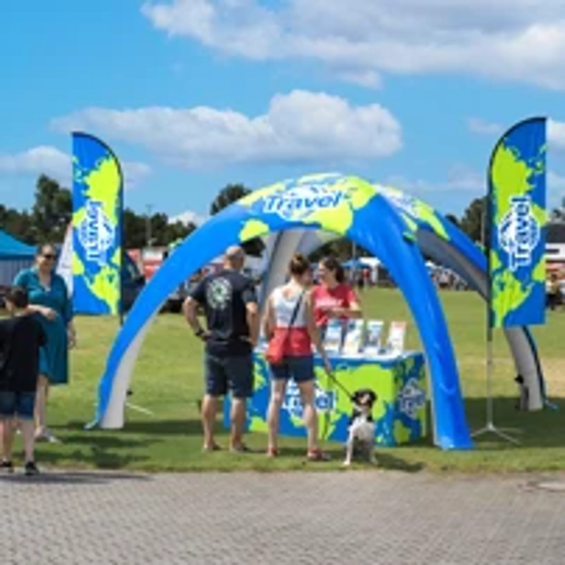 Blue custom inflatable dome tent with world map graphics serving as a travel agency promotional booth at an outdoor fair