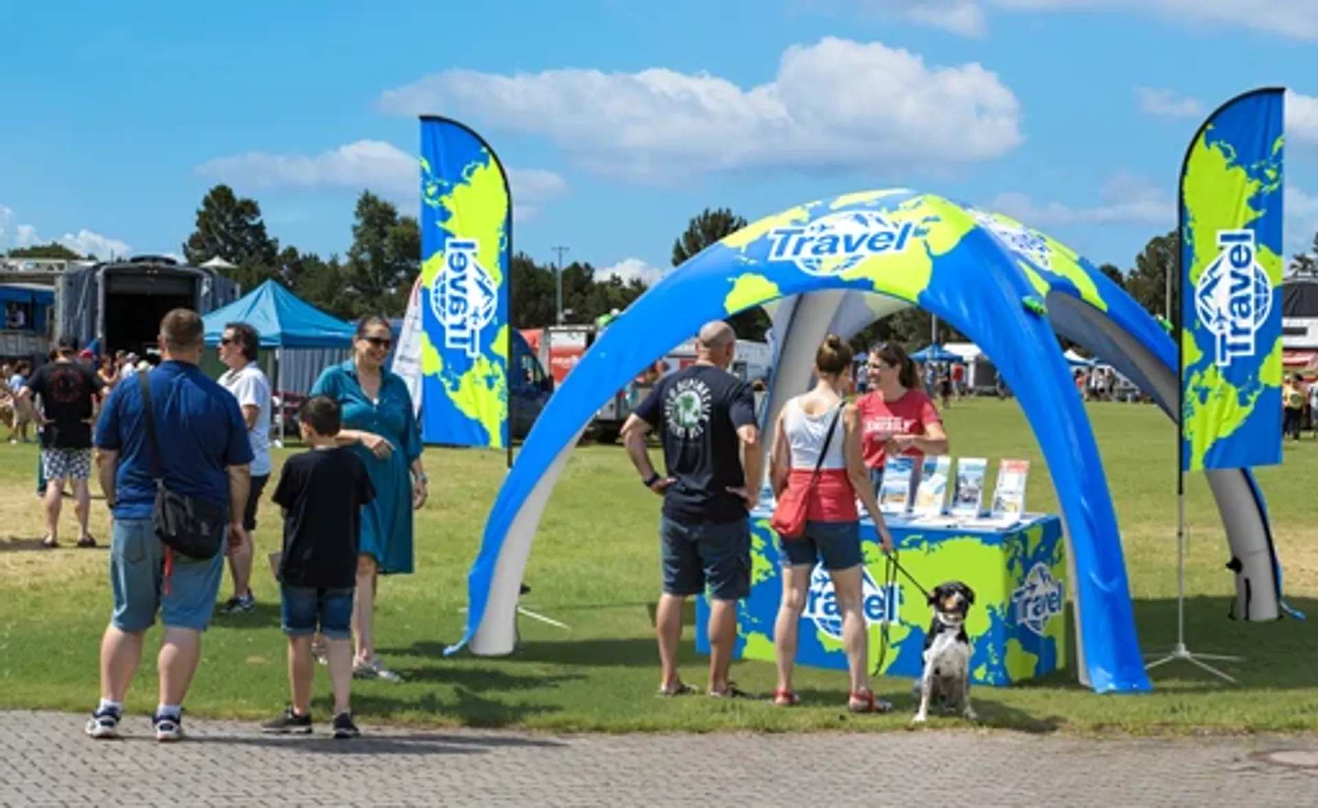 Blue custom inflatable dome tent with world map graphics serving as a travel agency promotional booth at an outdoor fair