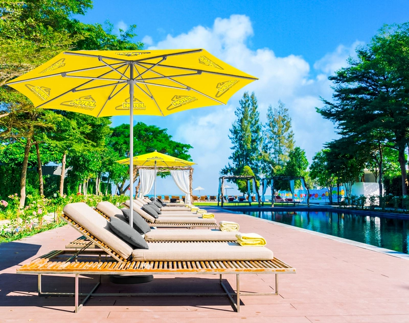 A custom patio umbrella providing shade for lounge chairs in a picturesque outdoor dining area