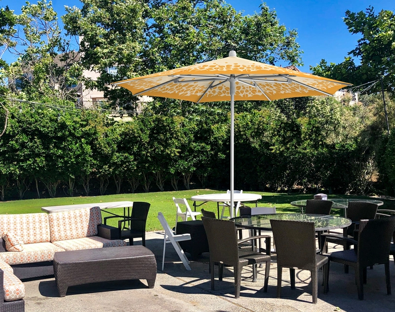 A serene outdoor dining area with lounge chairs and a vibrant custom umbrella providing shade