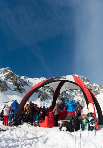Custom inflatable dome tent used as a branded shelter at a snowy mountain ski event.